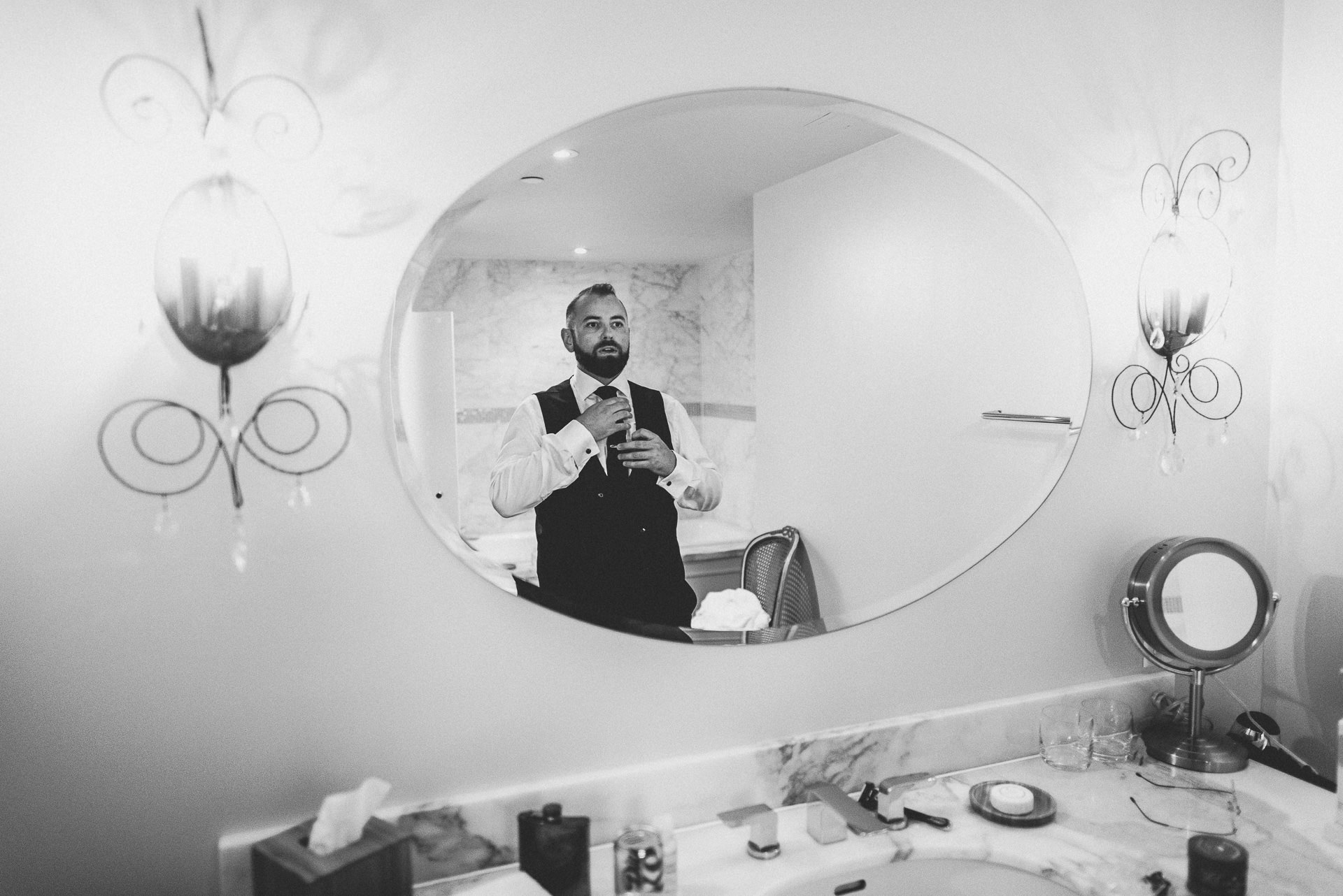 groom getting ready in mirror at the Ivy